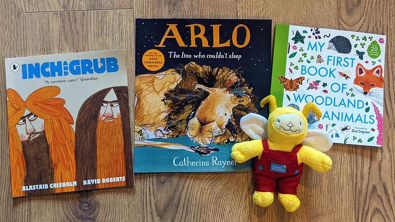 Three books (Inch and Grub, Arlo the lion who couldn't sleep, and My First Book of Animals) lying next to Bookbug doll